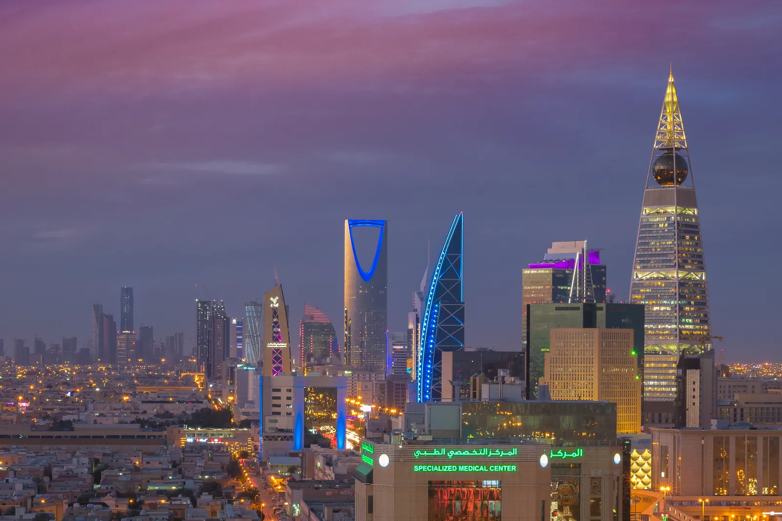 Riyadh skyline at dusk seen from Olaya, with Kingdom Centre and Al Faisaliah Tower lit up under a pink sky