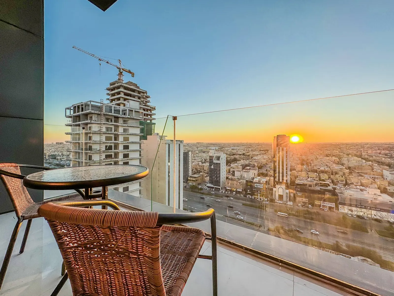 Balcony at sunset with a bistro table and chairs looking over northern Riyadh