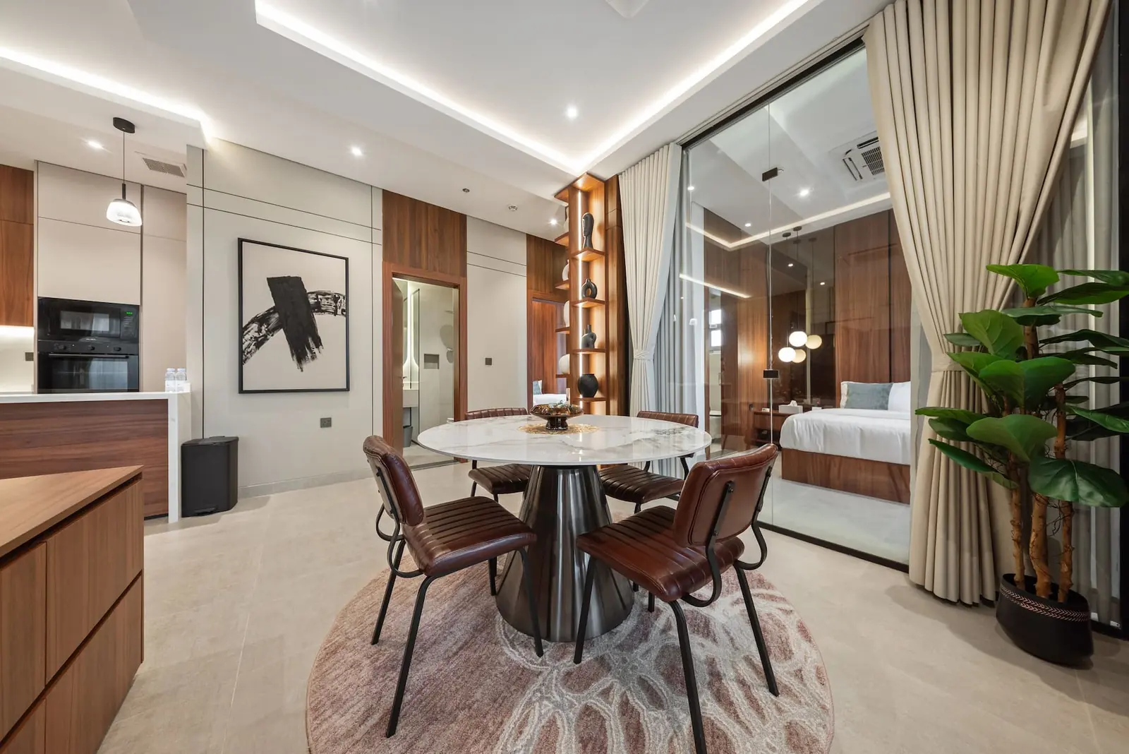 Round marble dining table with leather chairs beside the kitchen, bedroom beyond