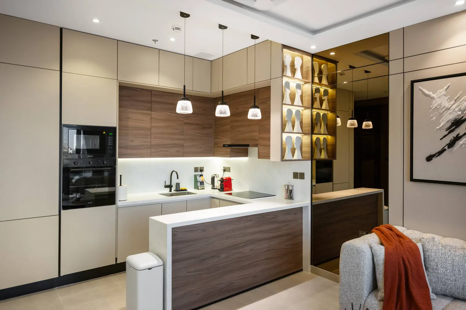 Kitchen with a built-in oven, island counter and glass display shelves