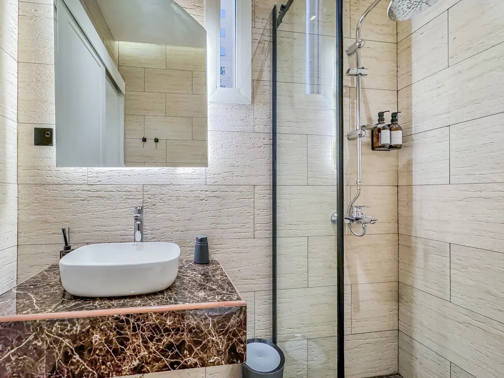 Luxury bathroom with rain shower and modern fixtures inside a spacious furnished apartment with pool in riyadh