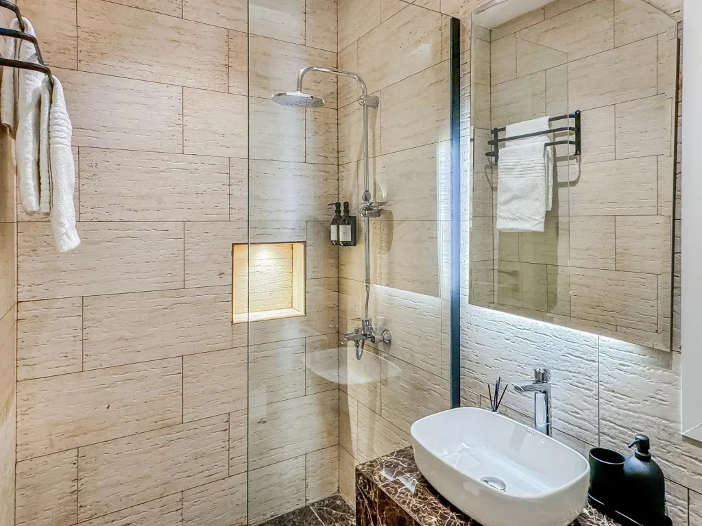 Stylish en-suite bathroom in a corporate serviced apartment near KAFD in Riyadh, showcasing elegant stone textures, modern vanity, and a clean, upscale aesthetic.