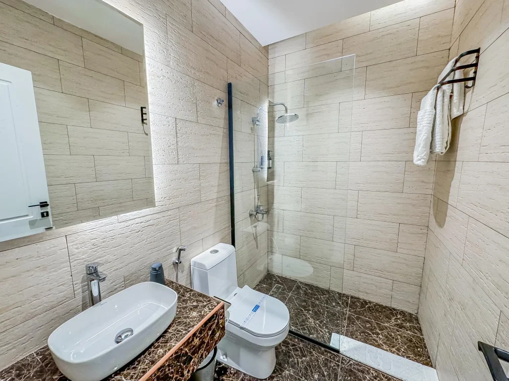 Luxury bathroom with rain shower and modern fixtures inside a spacious furnished apartment with pool in riyadh