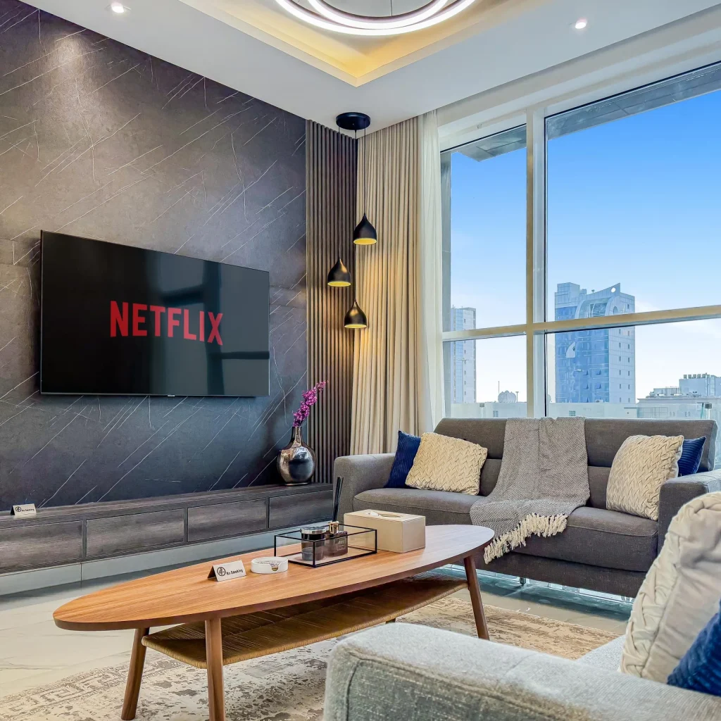 Bright and inviting corporate serviced apartment near KAFD in Riyadh living area, showcasing floor-to-ceiling windows, contemporary furniture, and city skyline views.