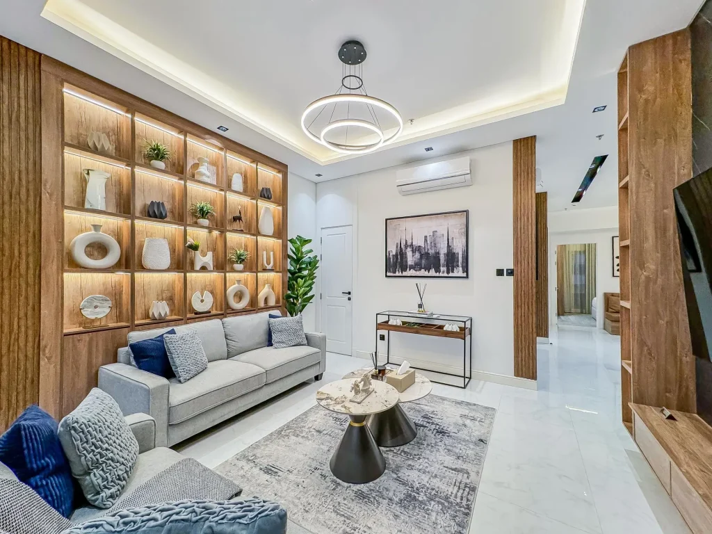 living room with curated shelves, and plush seating inside a high-floor furnished apartment with balcony.