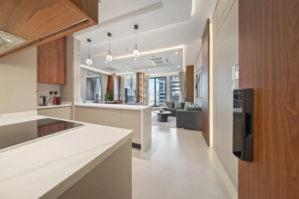 Modern serviced apartment near KAFD, featuring open-plan living room, L-shaped sofa, marble coffee table, and open kitchen